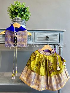 Expertly crafted, this Mehendi Green and Purple Kanchi Silk Skirt with Halter neck Top offers the perfect blend of style and comfort. The handmade tassels and back dori add a unique touch, while the halter neck top provides a chic and flattering fit. Perfect for any occasion. Fancy Clutch, Pleated Saree, Kids Wear Boys, Kids Wear Girls, Block Print Saree, Silk Saree Banarasi, Fancy Gowns, Silk Thread Bangles, Bridal Silk Saree