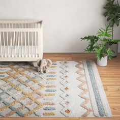 a baby crib next to a potted plant in a room with wooden floors