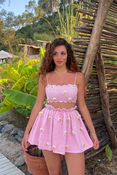 a woman standing next to a potted plant wearing a pink dress with daisies on it