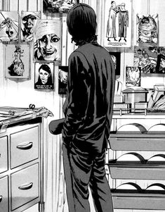 a black and white drawing of a man looking at pictures on the wall in his kitchen