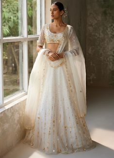 Embrace timeless elegance with the exquisite Ivory Embroidered Lehenga Set, crafted from pure silk organza. The full-length ivory lehenga showcases intricate hand-embroidery, adding a touch of opulence and tradition to the ensemble. Delicate motifs dance across the ethereal fabric, shimmering subtly in the light. Paired with matching half sleeved blouse features meticulous hand-embroidery, enhancing its luxurious appeal. A beautifully completed dupatta with hand-embroidered borders and motifs th White Cutdana Lehenga For Reception, Off White Wedding Choli With Cutdana, Off White Cutdana Choli For Wedding, Off White Cutdana Lehenga For Eid, Off-white Cutdana Lehenga For Eid, Wedding Lehenga In Off White With Cutdana, Elegant Off White Choli For Festive Occasion, Elegant Off White Festive Choli, Cream Floor-length Lehenga With Cutdana