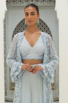 Ice blue longline jacket embroidered in tonal and silver beads, sequins and crystals and bell sleeves. Paired with a padded embroidered bustier and sharara.
Components: 3
Pattern: Embroidered
Type Of Work: Sequin, Bead, Crystal
Neckline: V Neck
Sleeve Type: Bell
Fabric: Net, Georgette
Color: Blue
Occasion: Wedding, Mehendi and Haldi - Aza Fashions Blue Bohemian Sharara For Reception, Party Blue Choli With Cape Sleeves, Blue Long Sleeve Choli With Dupatta, Bohemian Long Sleeve Sets For Wedding, Bohemian Long Sleeve Wedding Sets, Blue Long Sleeve Choli For Reception, Elegant Blue Outerwear With Intricate Embroidery, Bohemian Long Sleeve Lehenga For Party, Blue Long Sleeve Choli For Party