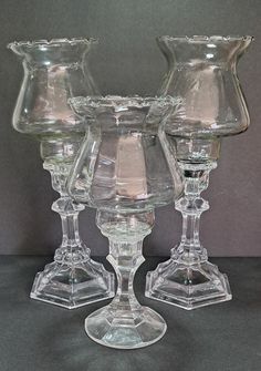 three clear glass goblets sitting on top of a table next to each other