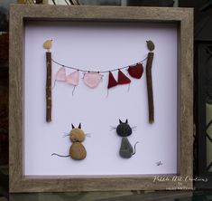 a shadow frame with three cats and a bird on it, hanging from a clothes line