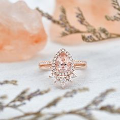 a pink diamond ring sitting on top of a table next to some rocks and flowers