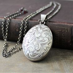 "This extra large sterling silver locket has a lovely swirling plume design etched on the front. The back of the piece, which has been engraved with the previous owners initials MEW, bears the traditional English hallmarks, made in Birmingham England in 1977. Opening reveals two spaces in which to place your beloved photographs.. The pendant is set on a new long sterling silver chain which has been antiqued to a rich charcoal gray. The chain has a little surprise at the end, tiny garnet stones f Vintage Sterling Silver Engraved Locket Necklace, Vintage Engraved Sterling Silver Locket Necklace, Ornate Engraved Antique Silver Locket Necklace, Antique Sterling Silver Etched Locket Necklace, Antique Etched Sterling Silver Locket Necklace, Ornate Silver Locket Jewelry, Oval Silver Locket Necklace For Vintage Collection, Silver Oval Locket Necklace For Vintage Collection, Vintage White Gold Jewelry With Engraving Option