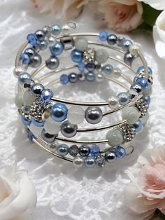 Imagine adorning your wrist with a masterpiece of elegance and sophistication, where every gleam of silver and every delicate hue of pale blue whispers tales of timeless beauty. Behold the enchanting allure of this four-coil stacked cuff memory wire beaded bracelet, a radiant symphony of craftsmanship and style. Crafted with meticulous attention to detail, this bracelet will form a graceful silhouette that gently embraces your wrist with understated glamour. As light dances upon its surface, the silver coils shimmer with a captivating brilliance, casting a spell of enchantment wherever you go. With every glance, you'll be reminded of the timeless allure of this exquisite creation, a reflection of your own impeccable taste. Elevate your style to new heights with this lovely piece, and let i Elegant Blue Stackable Crystal Bracelet, Light Blue Multi-strand Jewelry As Gift, Light Blue Multi-strand Jewelry Gift, Light Blue Multi-strand Jewelry For Gift, Elegant Handmade Light Blue Beaded Bracelets, Elegant Wire-wrapped Beaded Bracelets For Party, Silver Multi-strand Hand Wrapped Bracelets, Elegant Wire Wrapped Beaded Bracelets For Party, Elegant Party Beaded Bracelets Wire Wrapped