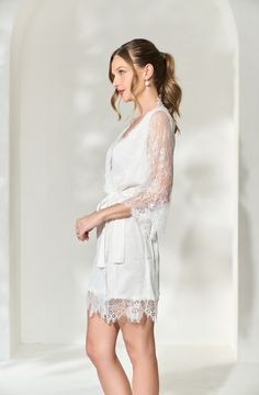 Made in a unique delicate white french lace design, the Lara Lace Robe is the perfect gift for the bride-to-be on her wedding day. Featuring scalloped lace edges along the neckline, hem and sleeve cuffs, this robe exudes old-world elegance. The body of the Lara Robe is fully lined to provide our brides the coverage they need. A slip dress is not required for under this robe, but if you're in search of one we recommend our White Bridal Slip Dress. Material: French lace with a fully lined bodySlee White Feminine Lace Top With Lace Trim, White Lace Bridesmaid Dress With Scalloped Lace, Elegant Lace Dress With Scalloped Lace For Wedding Night, Lace Dress With Lace Cuffs For Wedding Night, White Scalloped Lace Dress For Bridesmaid, Lace Wedding Dress With Lace Cuffs, Elegant Scalloped Lace Dress For Wedding Night, Elegant Lace Dress With Lace Trim For Wedding Night, Wedding Night Lace Patchwork Dress