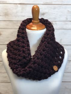 a crocheted cowl scarf on a mannequin headdress with buttons