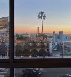 a view out the window of a building with cars parked in front of it at sunset