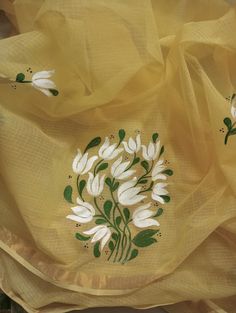 an embroidered yellow fabric with white flowers on the bottom and green leaves in the middle