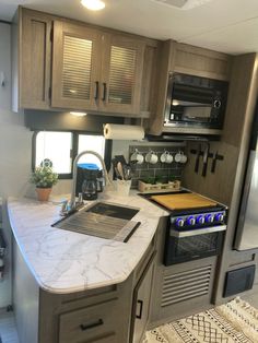 a kitchen area with an oven, microwave and sink in a recreational vehicle or motor home