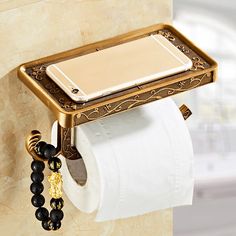 a phone is hanging on the wall next to a roll of toilet paper and a beaded bracelet