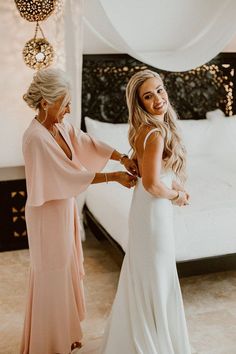 two women standing next to each other in front of a bed