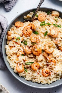 a bowl filled with rice and shrimp on top of a white table cloth next to a fork