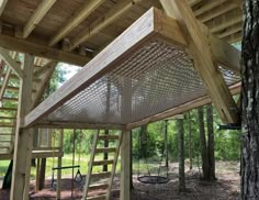 a wooden structure in the middle of a forest with stairs leading up to it's roof