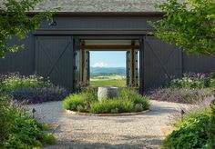 an open barn door leading into a lush green field with purple flowers and lavenders