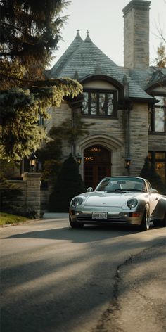 a white sports car is parked in front of a large house with a tower on top