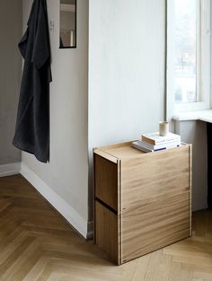 a wooden cabinet sitting in the corner of a room next to a window with a towel hanging on it