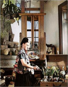 a woman standing in front of a table filled with vases and other items on it