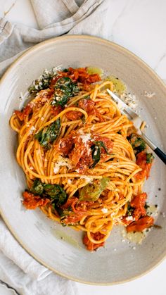 a plate of pasta with tomato sauce and parmesan cheese on top, next to a fork