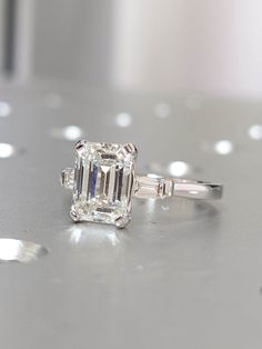 an emerald cut diamond ring on a table