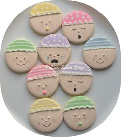 six decorated cookies on a plate with eyes and noses painted to look like children's faces