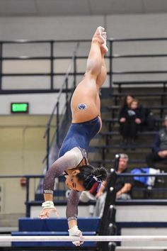 a woman is doing a handstand on the beam