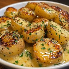 a white bowl filled with potatoes covered in gravy and garnished with parsley