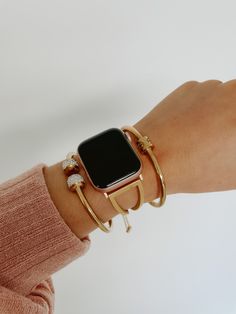 an apple watch on someone's arm with gold rings and bracelets around it