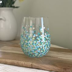 two vases sitting on top of a wooden table with blue and white confetti in them