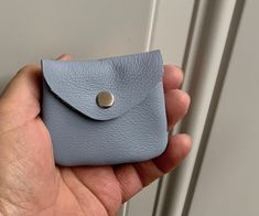 a hand holding a blue leather wallet with a button on the front and back side