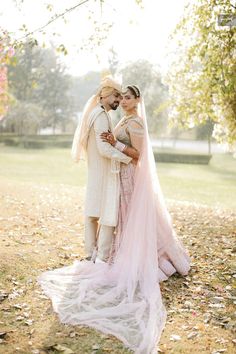 a bride and groom pose for a photo in their wedding dress on the grass with leaves all around them