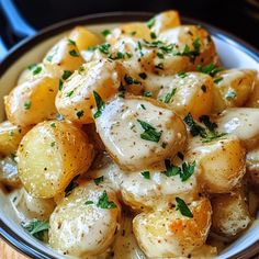 a bowl filled with potatoes covered in gravy and garnished with parsley