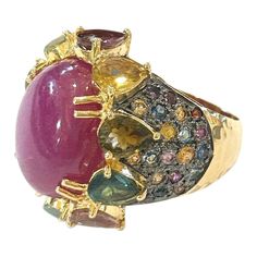 This is part of Chairish’s Fine Jewelry assortment.  Center Oval Shape Natural Ruby - 4 Carat  Multi color Natural Sapphires from Sri Lanka 2.50 Carat  Round and Pear shape Brilliant Colors: Pink, Yellow, Rose, Green and Blue   This Ring is from the "Orient" traveling collection are the epitome of elegance and versatility. It offers a perfect blend of day to night and swimwear to evening wear, allowing you to effortlessly transition between different occasions and outfits.  Wearing these spectac Luxury Multicolor Sapphire Ring, Luxury Multicolor Sapphire Ring For Formal Occasions, Luxury Ruby Ring With Cabochon Cut, Luxury Multi-stone Ruby Ring, Luxury Collectible Sapphire Ring, Luxury Multicolor Multi-stone Sapphire Ring, Luxury Multicolor Sapphire Ring With Gemstone Accents, Luxury Multicolor Ruby Ring, Luxury Ruby Ring With Gemstone Accents For Anniversary