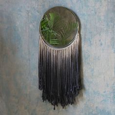 a mirror hanging on the side of a wall next to a palm leaf and plant