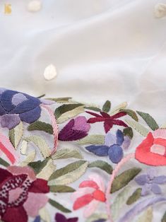 a close up of an embroidered fabric with flowers and leaves on the back of it