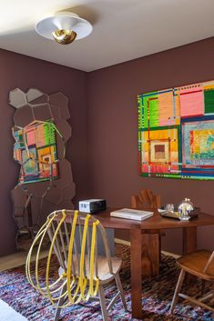 a dining room table with chairs and artwork on the wall