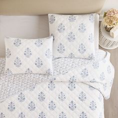 a white and blue quilted bed with pillows