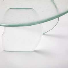 a glass table with a curved base on the top and bottom, against a white background