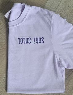 "This Listing is for our Totus Tuus, Totally Yours, embroidered Catholic t-shirt. It is a beautiful Marian t-shirt; in Latin, the phrase, \"Totus Tuus,\" means \"totally yours\", a motto from JPII, who had a great devotion to our blessed Mother.  When placing your order, in the personalization box, please include the following information: 1.) Two Thread colors (one for \"TOTUS TUUS\" and one for \"Totally Yours\" If no thread color is entered, we will automatically use colors as shown in the sa Purple Cotton Tops With Embroidered Text, Pocket Oratory, Catholic Fashion, Catholic Shirts, Catholic Clothing, Catholic Shirt, Catholic Tshirts, Minimalist Shirts, My Shopping List