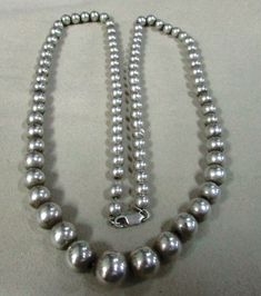 "Graduated sterling silver bead necklace. 25 1/4\" long. The center bead is 12 mm. The smallest beads in back are 6 mm. The beads are strung on chain and have a lobster claw clasp. There is some natural patina on the beads so the look is softer, not too bright and shiny. Good condition. This is a classic timeless look. Good condition. BDS-2" Hand-strung Sterling Silver Necklace In Silver, Hand-strung Sterling Silver Necklace, Sterling Silver Single Strand Beaded Necklace, Silver Round Beaded Necklaces Hand-strung, Elegant Silver Beaded Necklaces Hand-strung, Elegant Silver Hand-strung Beaded Necklaces, Hand-strung Silver Beaded Necklace, Silver Beaded Necklace With Large Sterling Beads, Silver Beaded Necklace With Sterling Silver Clasp