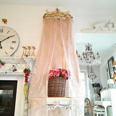 a living room with a fireplace, clock and pink curtains