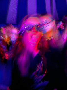 blurry photograph of people dancing in an open area with blue and purple striped walls