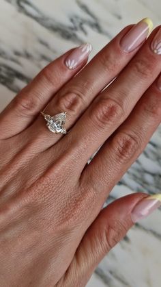 a woman's hand with pink and yellow manicured nails holding an engagement ring