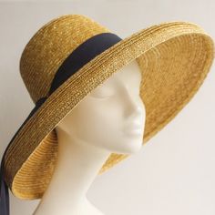 Mirabele Natural Straw Sun Hat with face shading wide brim, deep crown in golden antique colour straw and classic 'darkest navy petersham ribbon decoration. Travel in style. A chic, romantic and versatile hat for country walks, gardening, city strolls and outdoor activities... sea and sand... for summer gatherings. Team up with play suits, printed tea dresses, neutral ensembles, beach wear, trouser suits or smart jeans and wear it all summer long. Limited edition.   SHIPPING All shipments will b Gold Brimmed Straw Hat, Gold Wide-brim Straw Hat For Kentucky Derby, Gold Wide Brim Straw Hat For Kentucky Derby, Gold Brimmed Straw Hat For Kentucky Derby, Gold Wide Brim Straw Hat, Adjustable Gold Panama Hat With Wide Brim, Adjustable Gold Straw Hat For Kentucky Derby, Gold Brimmed Sun Hat For Kentucky Derby, Gold Curved Brim Hat For Kentucky Derby