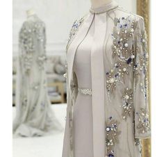 a white dress and jacket on display in a room with other dresses behind it,