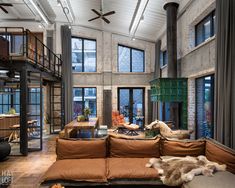 a large living room with high ceilings and lots of windows on the wall, along with an orange couch