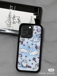 an iphone case with swans and flowers on it next to a card holder for the phone