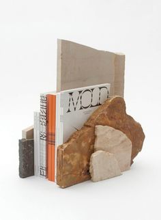 two books are stacked on top of each other in front of a rock and bookend